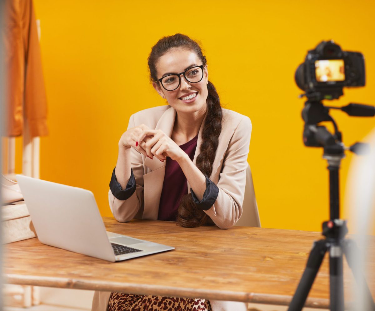 Portrait of contemporary young woman smiling at camera in studio while filming video for beauty and lifestyle channel, copy space